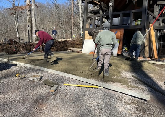 Crew finishing a concrete walkway alongside a gravel driveway