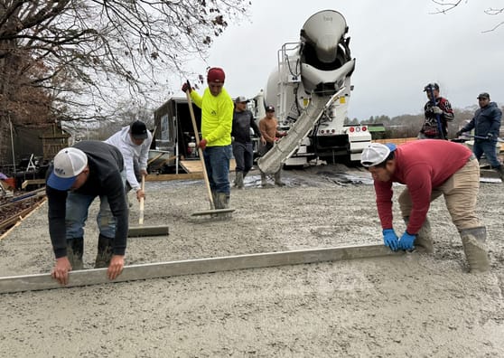 Crew placing and levelling concrete from a mixer chute